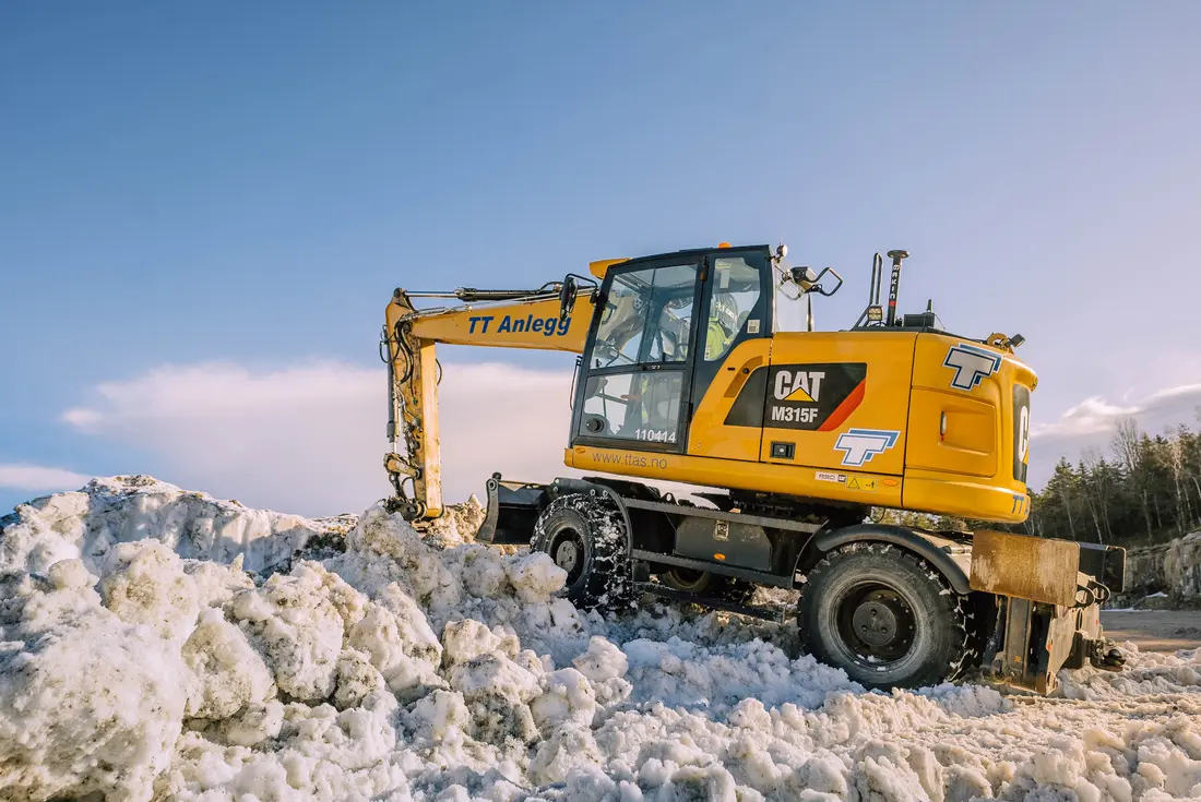 Gravemaskin med anleggskjetting i snø